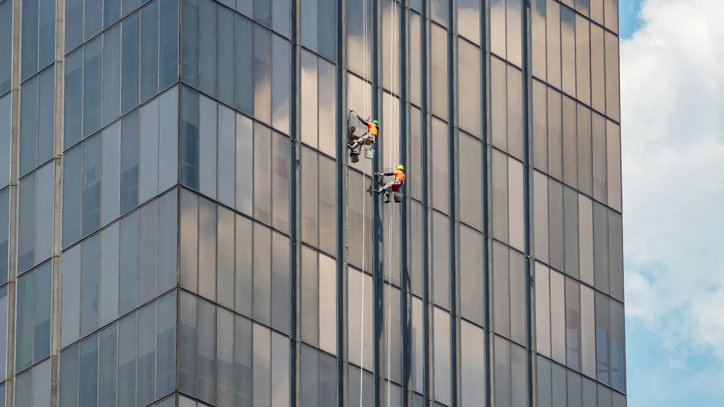 Profissionais realizando limpeza de vidros em fachada corporativa